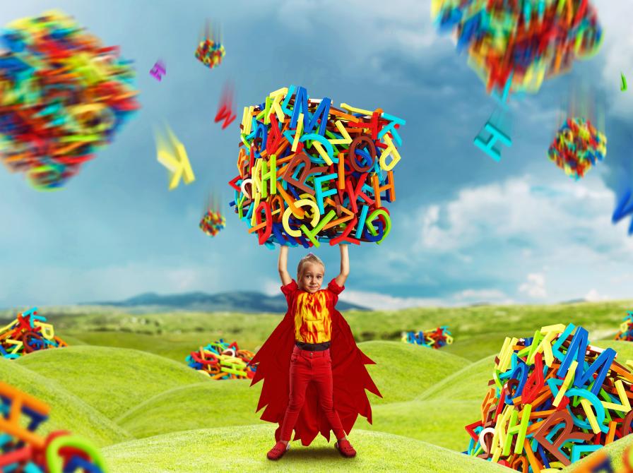 Barn holder en stor kasse lavet af bogstaver i begge hænder over hovedet